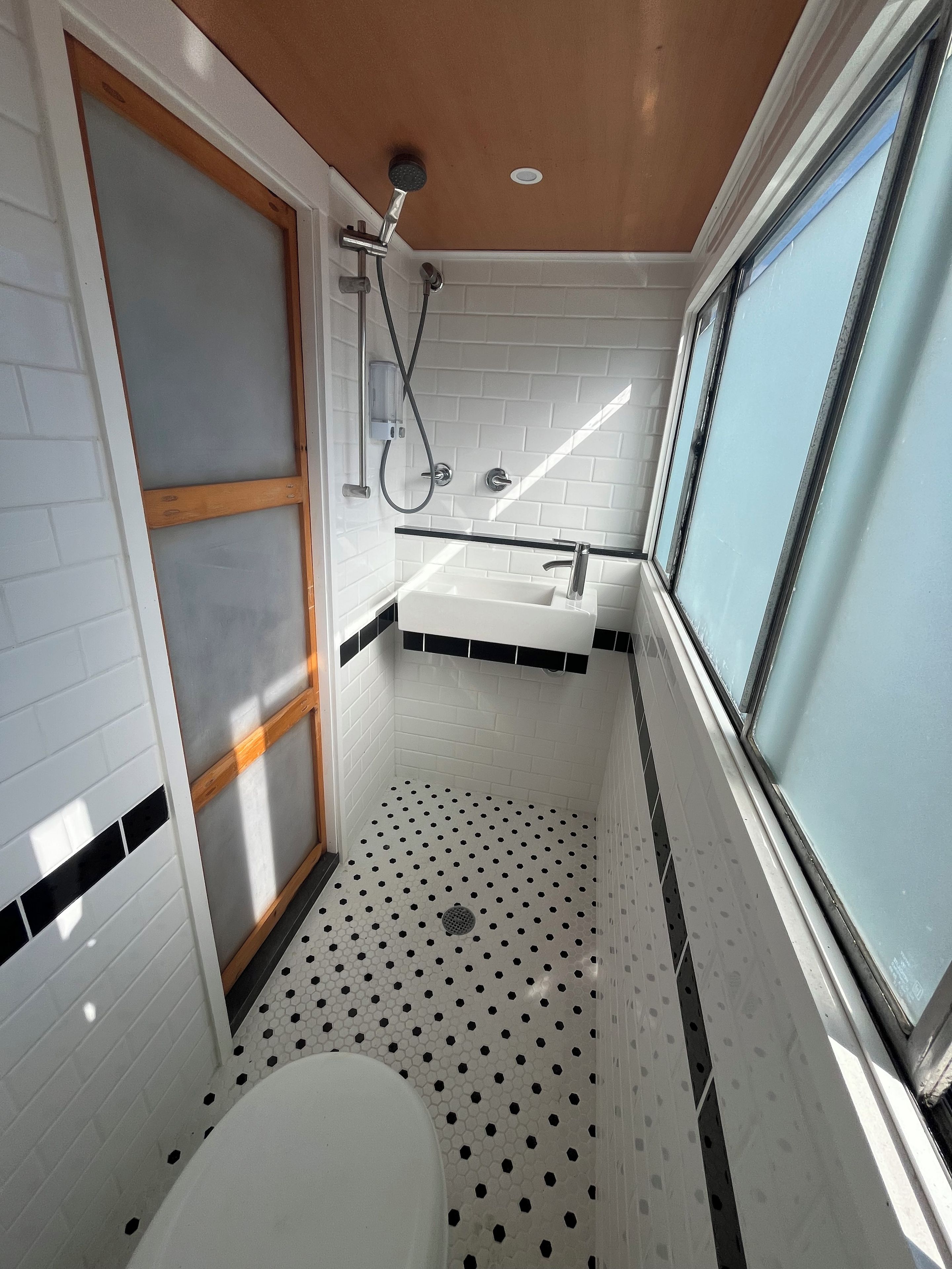 Een badkamer met douche, toilet en wastafel.