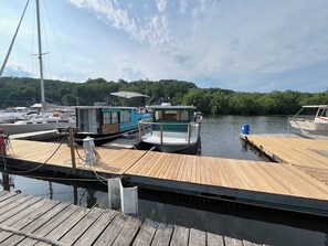 A marina with docked boats, a wooden pier, and a backdrop of trees.