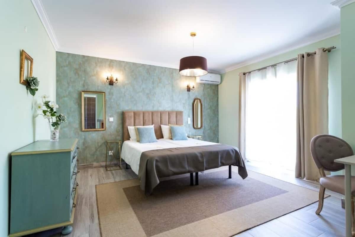 A bedroom with a bed, bedside tables, a dresser, a mirror, and a window with curtains.