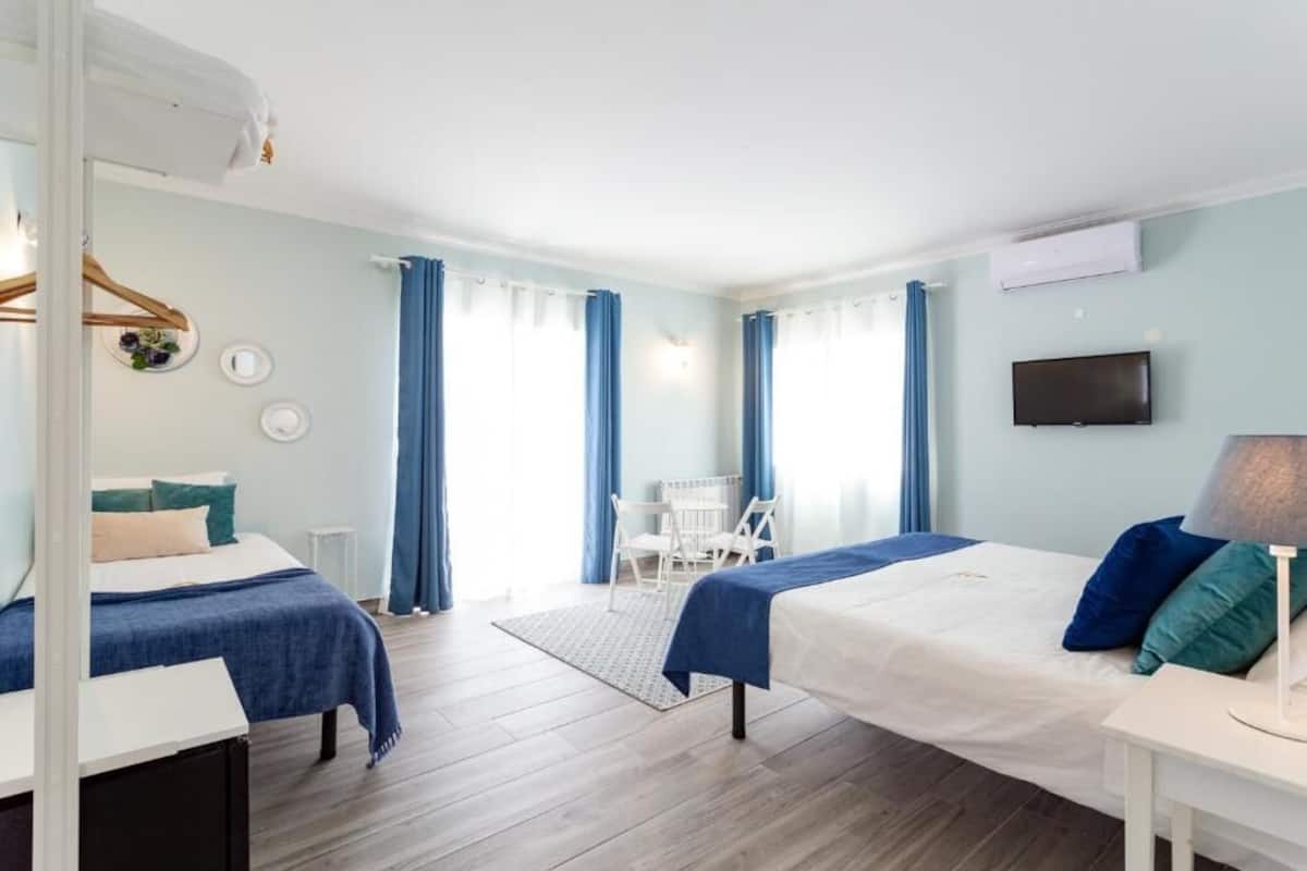 A hotel room with two beds, a TV, a desk, and a chair.