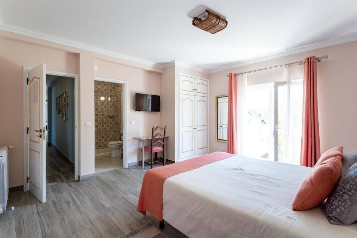 A bedroom with a bed, a television, a wardrobe, and a bathroom.