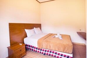 A single bed with a wooden headboard, a bedside table, and a checkered bed skirt.