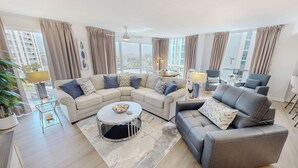 Un salon spacieux avec un canapé d’angle, une table basse ronde et un fauteuil gris.