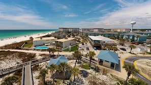 Ein Hotel an der Küste mit Blick auf den Strand, mehreren Gebäuden, einem Schwimmbad und einem Parkplatz.