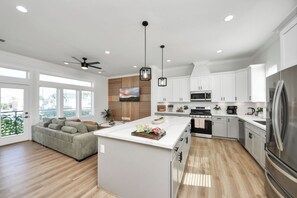 A modern kitchen with white cabinets, a large island, and a ceiling fan.