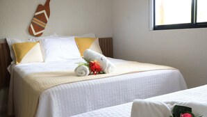 A hotel room with a bed, pillows, a decorative wall piece, and a window.