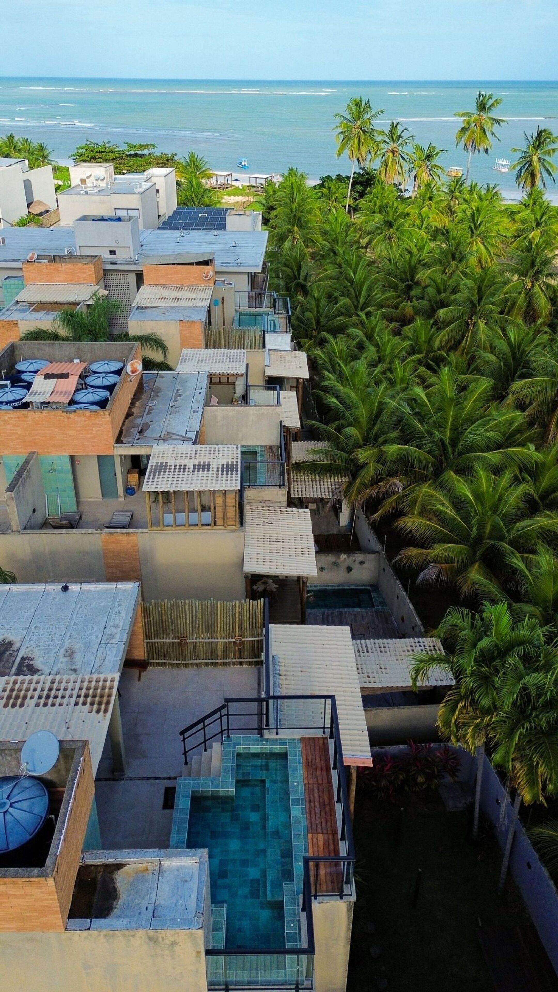 Área residencial com vários edifícios, piscina e vista para o oceano.