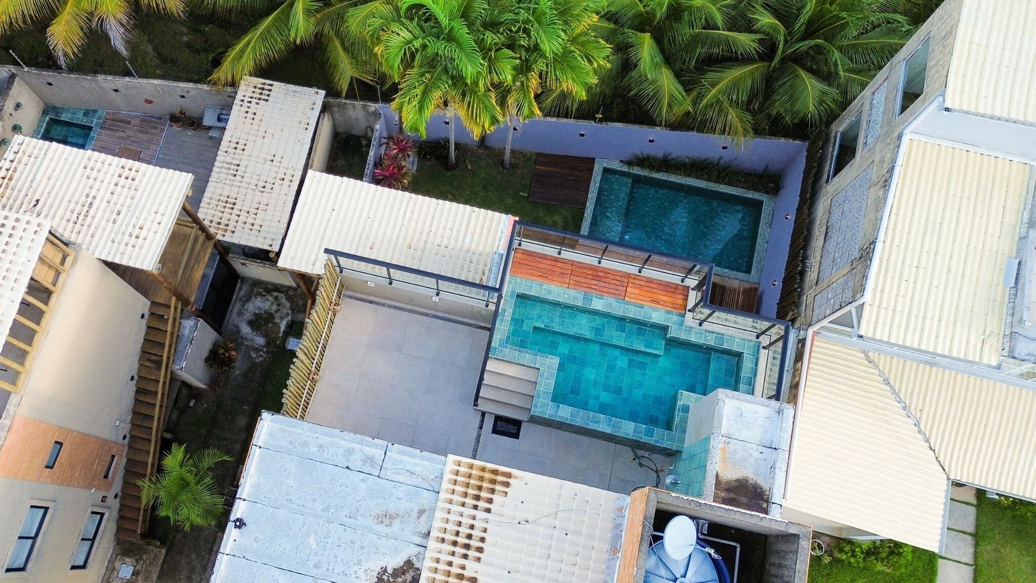 A residential area with a swimming pool, multiple buildings, and palm trees.