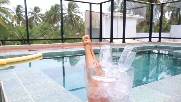 Zona de piscina con una botella de champán en un balde de hielo, un flotador amarillo y un vaso de plástico transparente.