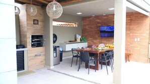 Una cocina moderna con horno empotrado, un comedor con mesa y sillas, y un televisor montado en la pared.