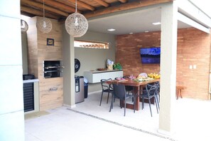 A modern kitchen with a built-in oven, a dining area with a table and chairs, and a TV mounted on the wall.