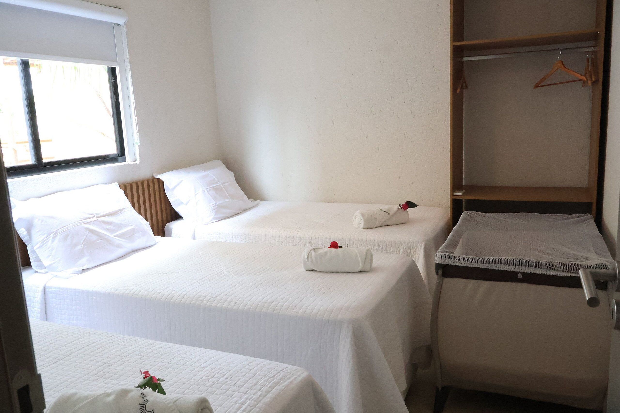 A hotel room with two beds, a window, and a wardrobe.