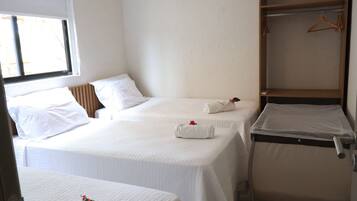 A hotel room with two beds, a window, and a wardrobe.