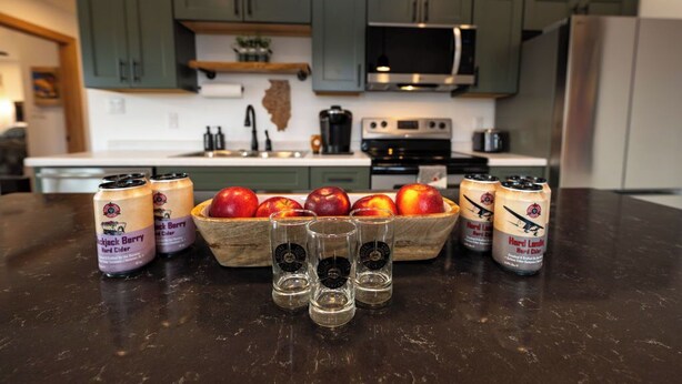 A kitchen with green cabinets, a microwave, a stove, and a fruit bowl with apples. - Cozy well-appointed Guest Suite on a grass airstrip (Hanover)
