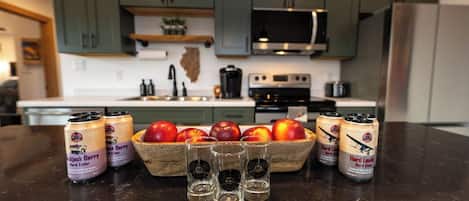A kitchen with green cabinets, a microwave, a stove, and a fruit bowl with apples.