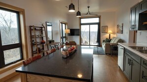 A modern kitchen with a central island, wooden cabinets, and a dining area with a sofa and chairs. - Cozy well-appointed Guest Suite on a grass airstrip (Hanover)