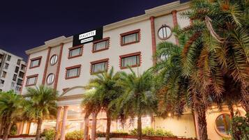 A hotel with a sign reading 'PALETTE Company Services,' featuring a modern facade with multiple windows and a well-lit entrance.