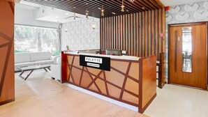 Un comptoir d’accueil avec une pancarte indiquant « PALETTE & Company – Services », des lambris en bois au plafond, un canapé et une porte portant l’inscription « RESTAURANT ».