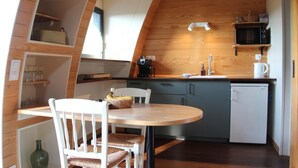 Une cuisine compacte avec un coin repas, des murs en bois et un réfrigérateur blanc.