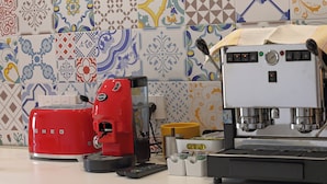 A kitchen with a red coffee maker, a coffee machine, and a coffee grinder on the counter. - francescosuite b&b (Sorrento)
