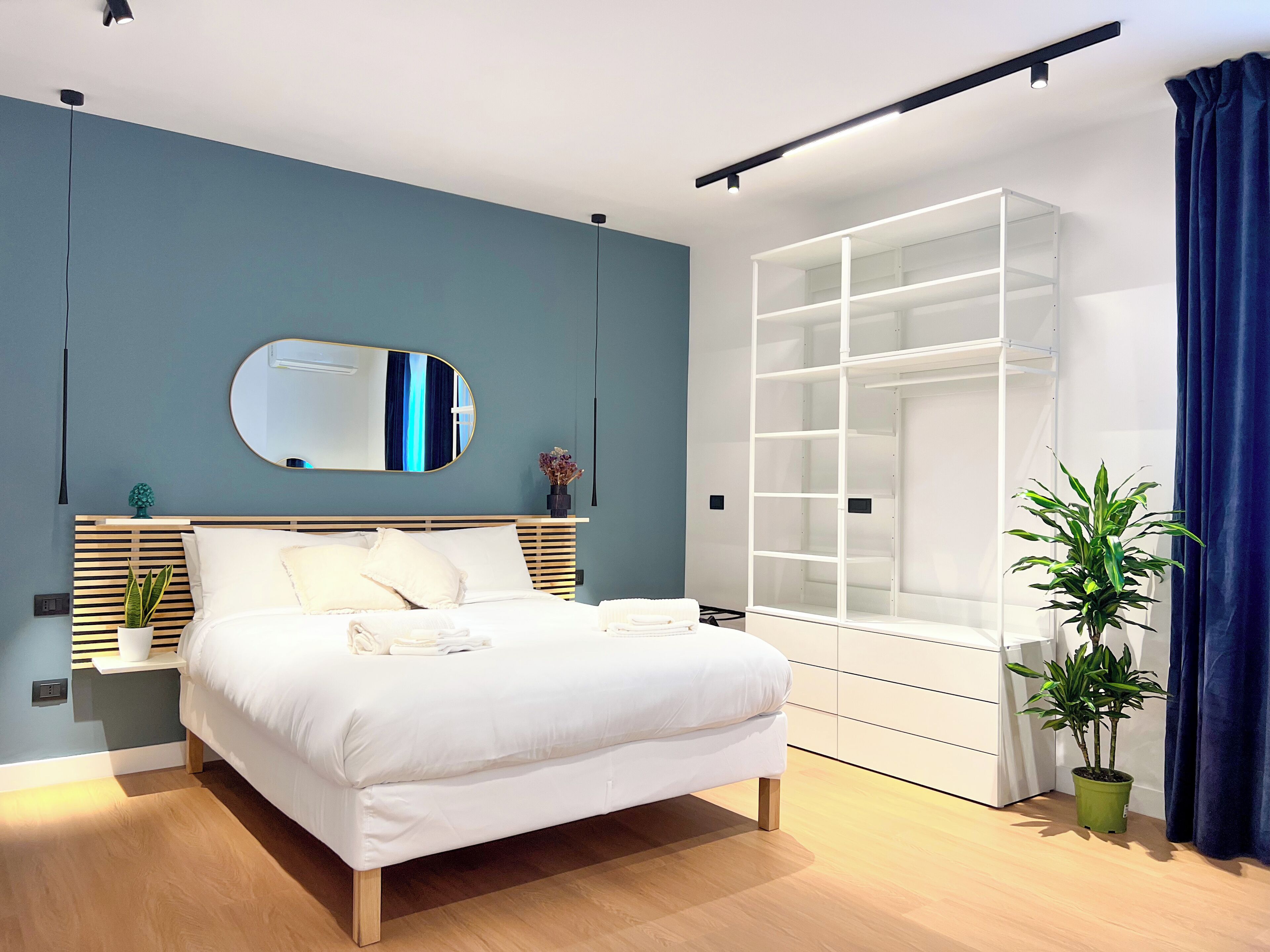Quarto moderno com cama, espelho, guarda-roupa embutido e um vaso com planta.