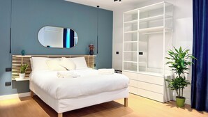 Ein modernes Schlafzimmer mit einem Bett, einem Spiegel, einem Einbauschrank und einer Topfpflanze.