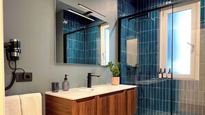 Ein modernes Badezimmer mit einem Holzbadezimmer-Möbel, einem großen Spiegel und einer Duschkabine aus Glas.