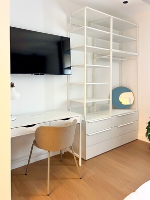 A room with a desk, chair, TV, and a white shelving unit. - April Suites Apartments - Suite 3, Turquoise (Palermo)
