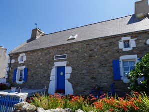 A stone building with a blue door and shutters, a small window, and a flag on top. - Sea View Family Stay in Plouarzel (Plouarzel)