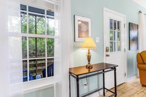 A room with a window, a table with a lamp, and a door. - 🏡🌴Quaint 3BR Cottage w/ Community Pool | Walk to Beach | The Rookery 3602 (Fort Morgan)