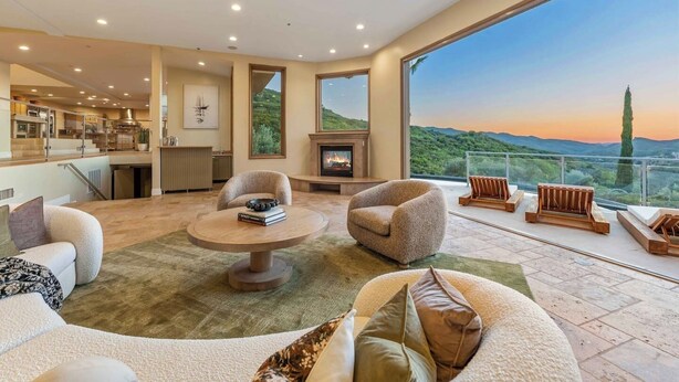 A spacious living area with a fireplace, comfortable seating, and a large window offering a view of the landscape.