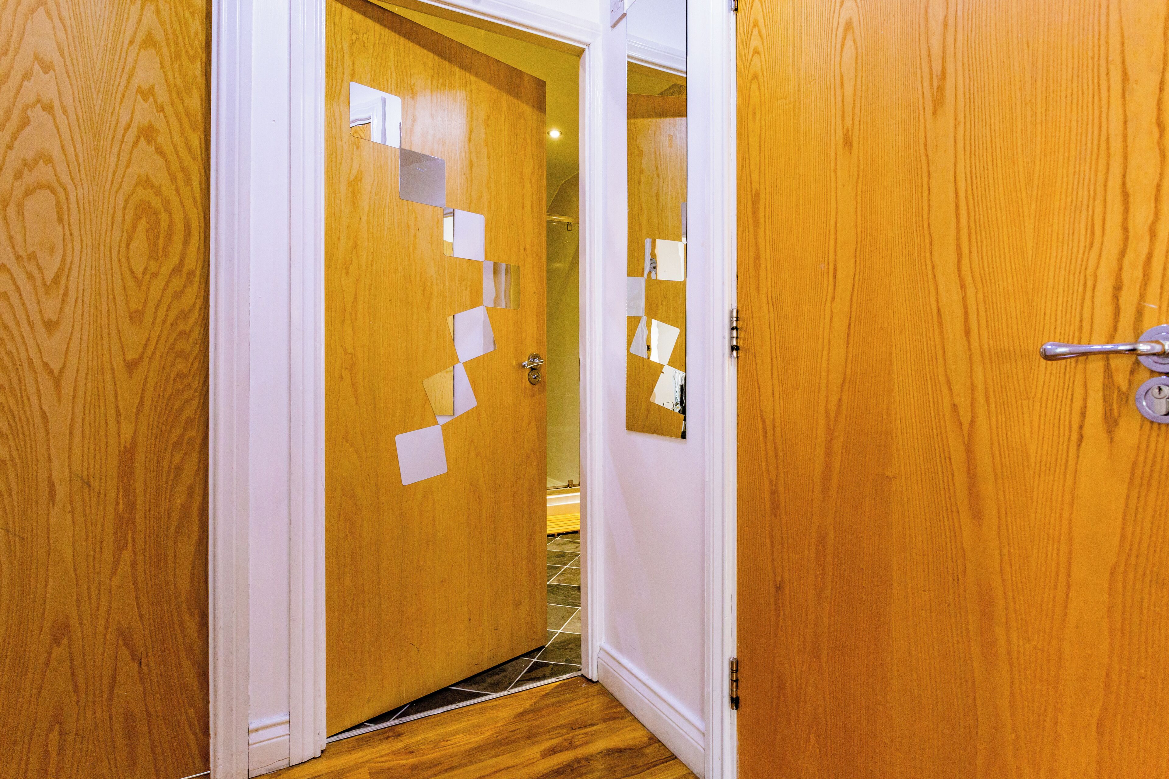 Une porte en bois, dotée d’un cadre blanc et d’une poignée en métal.