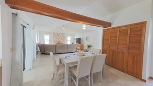 A dining area with a table set for four, a sofa in the background, and a wooden wardrobe. - Coastal Comfort in Port St. Lucie – Open Plan Home - Summer Fun winter Escape (Port st Lucie)
