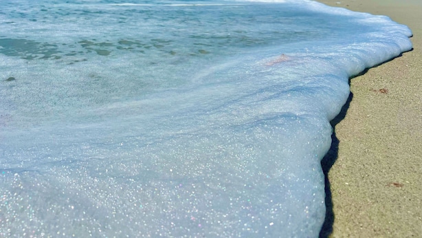 Een strand met golven die rustig op de kust spoelen.