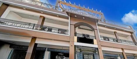 A multi-story hotel with a prominent entrance archway and a sign reading 'Evergreen Clark's Inn.'