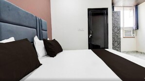 A hotel room with a bed, a door, a window, and a wall-mounted air conditioner. - Hotel Evergreen Clarks (Lucknow)