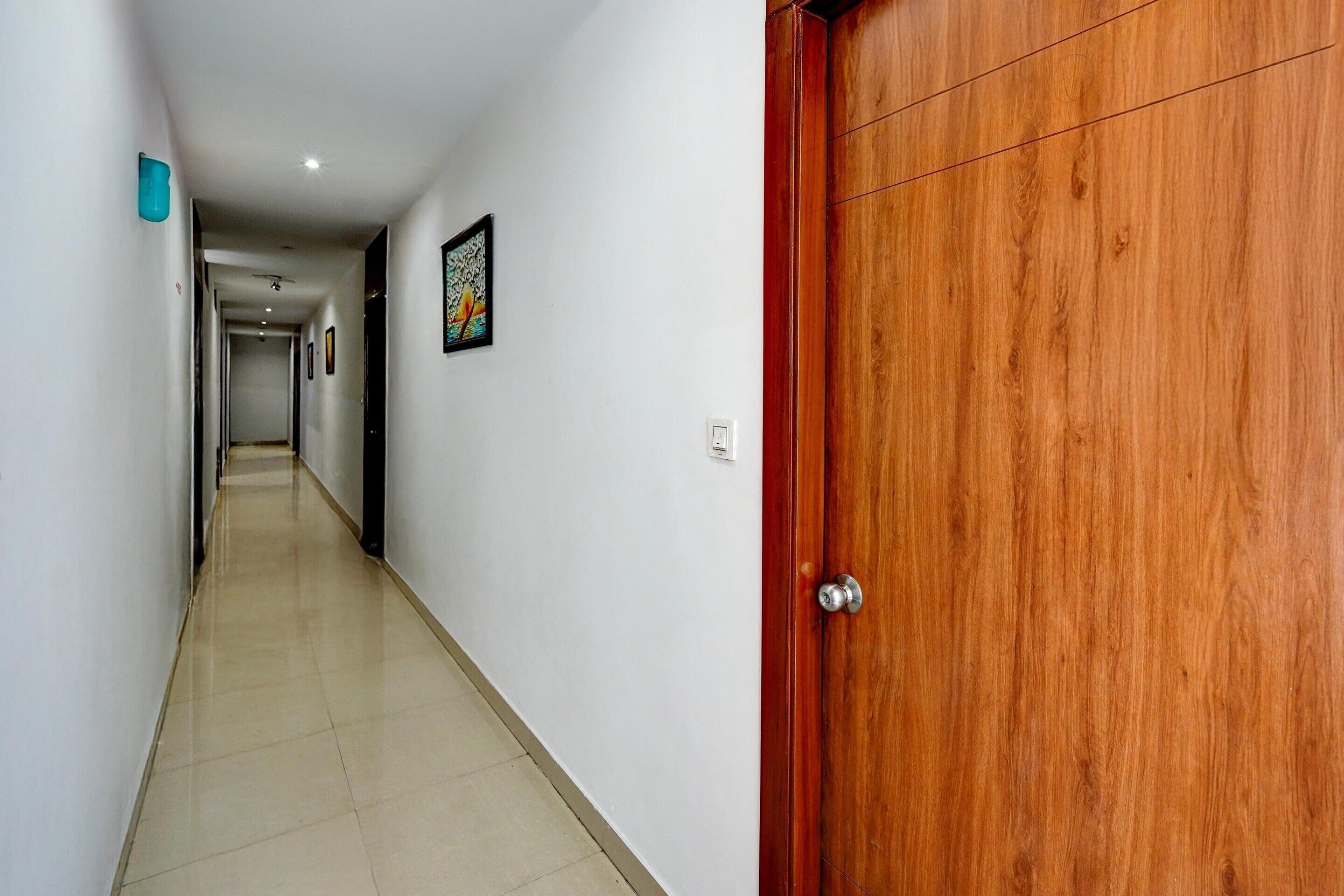 A hallway with a wooden door, white walls, and a tiled floor.