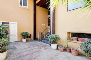 A paved courtyard with potted plants, a staircase, and a door.