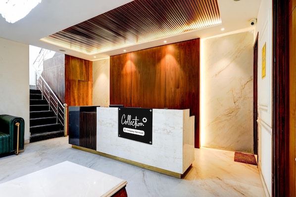 A reception desk with a sign, a staircase, and a marble floor.