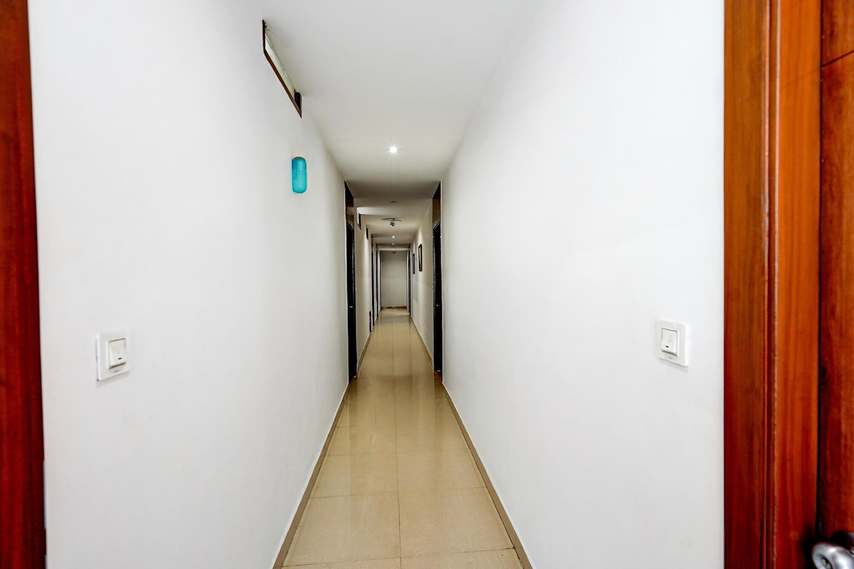 A long, narrow hallway with white walls and a wooden door on the right.