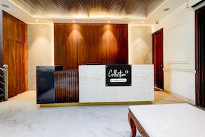 A reception desk with a marble countertop, wooden paneling, and a sign indicating company service.