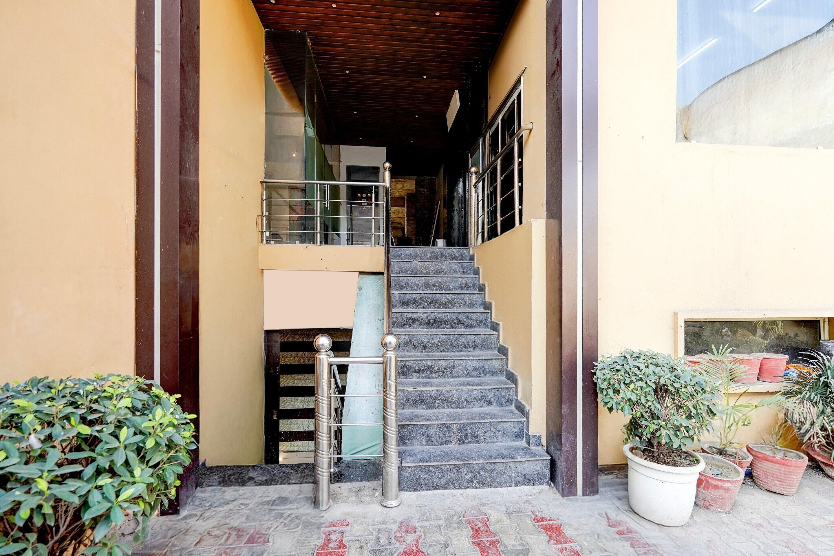 A staircase leading to an upper level, potted plants, and a metal railing.