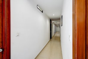 A corridor with white walls, wooden doors, and a tiled floor.