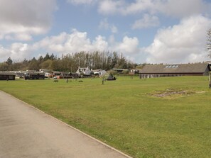 A grassy field with a building, picnic tables, and a clear sky. - Lochwood Platinum Superior at Three Lochs Holiday Park (Newton Stewart)