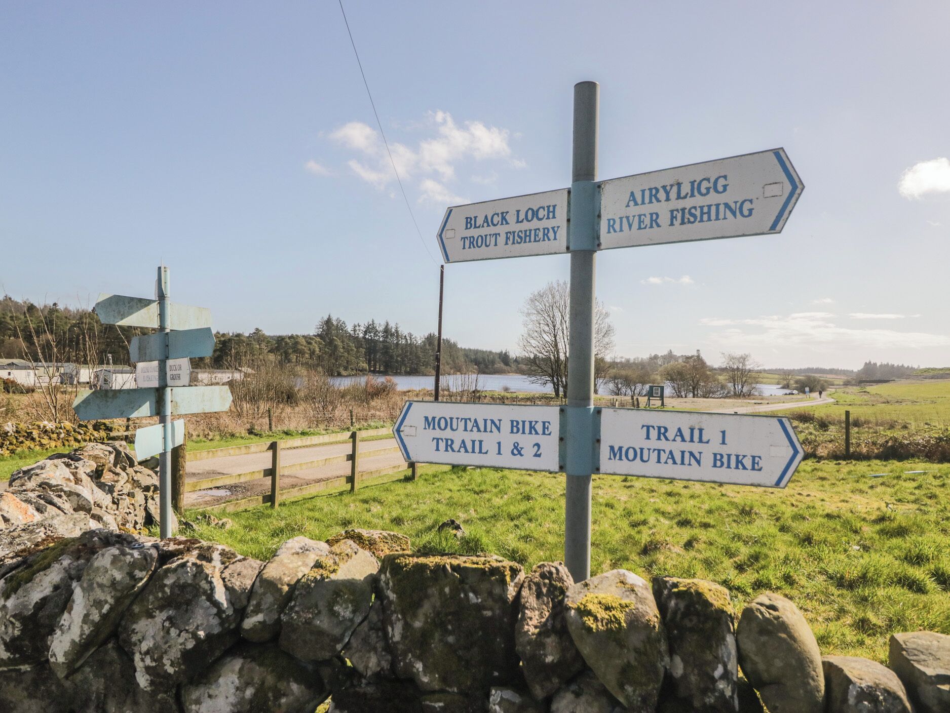 Directional signs for Black Loch Trout Fishery, Airy Lighg River Fishing, and trails for mountain biking.
