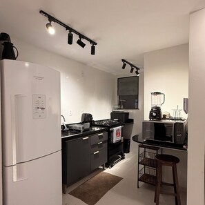 Eine moderne Küche mit Kühlschrank, Herd, Mikrowelle und Kaffeemaschine.