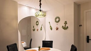 Een eetkamer met een ronde tafel, zwarte stoelen, een hanglamp en decoraties met een nautisch thema.