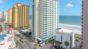 Ein Hochhaus-Hotel mit mehreren Stockwerken, einem Schwimmbad und Blick auf den Strand.