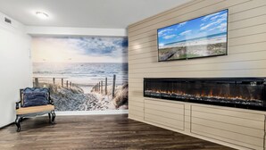Une chambre avec une fresque représentant une plage, un téléviseur à écran plat, une cheminée et un plancher en bois.
