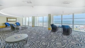 Une pièce spacieuse avec un tapis à motifs, des tables rondes et des chaises bleues.